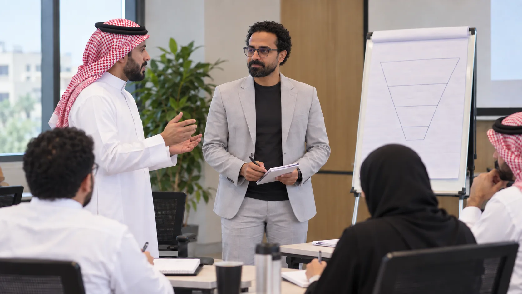 خلال ورشة عمل، أشرف إبراهيم يشرح مخططًا على لوح ورقي للمشاركين الجالسين حول الطاولة